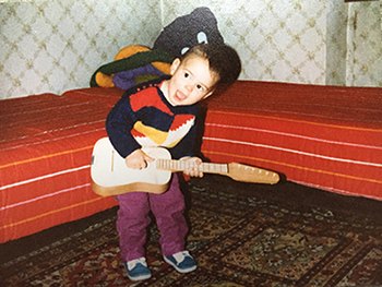 Phillip Kaminiak as a child, playing a toy guitar